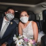 A bride and groom wearing face masks on their wedding day in a car driving towards the reception at Fleetwood Farm Winery.