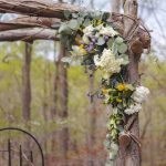 A wedding arch adorned with flowers in the woods.