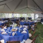 A detailed wedding reception featuring tables and chairs set up in a tent.