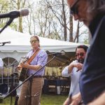 A group of men candidly preparing music for a wedding in a tent.