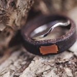 A leather wedding ring is sitting on top of a piece of wood, showcasing intricate details.