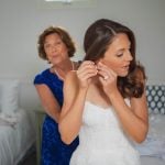 A candid bride assisting her mother during wedding preparations.