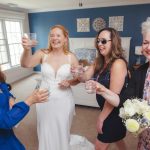 A group of bridesmaids candidly toasting in preparation for the wedding.