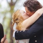 A wedding ceremony in the woods with a bride and groom kissing.