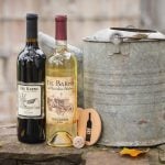 A wedding detail featuring two bottles of wine and a bucket on a stone wall.