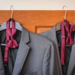 Two suit jackets hanging on a door, showcasing wedding attire.