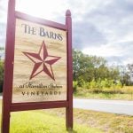 The bard's vineyard sign in front of a country road, featuring wedding details.