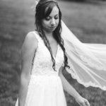 Black and white portrait of a bride holding her veil at her wedding.