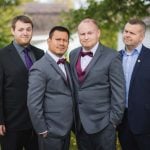 Four men in suits posing for a wedding portrait.