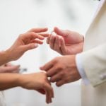 A couple participating in a wedding ceremony exchanging wedding rings.