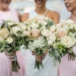 Four bridesmaids holding pink and white bouquets at a wedding.