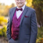 Wedding groom in a gray suit with a purple bow tie.