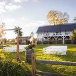 A detailed wedding ceremony set up in a field with white chairs.