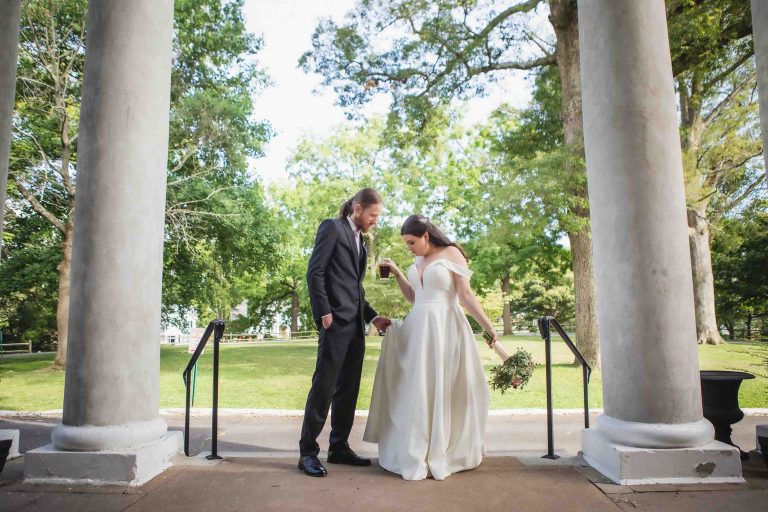 A wedding portrait of a bride and groom in front of pillars.