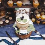 A detailed wedding cake with cupcakes displayed on a table.