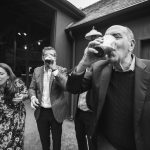 A black and white photo of a group of people drinking at a wedding reception.