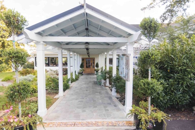 A walkway leading to a house with plants and flowers suitable for a portrait.