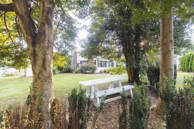 A white picnic table sits in the middle of a yard, suitable for a wedding.