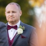 A man in a suit is looking at another man during a wedding ceremony.