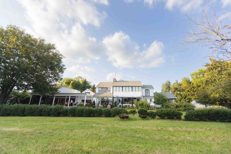 A picturesque white house nestled in a peaceful grassy field, perfect for outdoor wedding portraits.