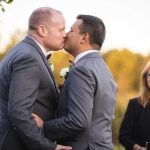 During their outdoor wedding ceremony, a groom affectionately kisses his bride.