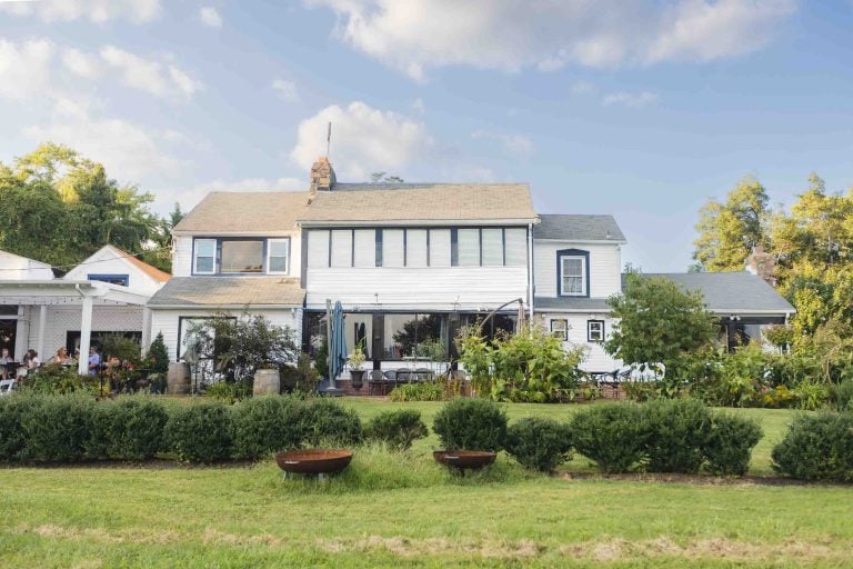 A large white house in the middle of a green field, perfect for wedding portraits.