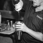 A man pouring a drink at a wedding reception.