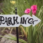 A sign displaying wedding details in front of flowers.