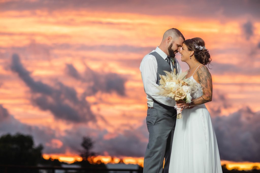 A wedding couple share a sunset portrait.