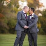 Portrait of two grooms in suits at their wedding.