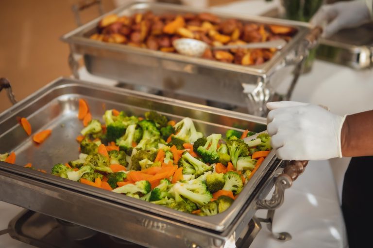 A person is preparing food with attention to details for a wedding buffet.