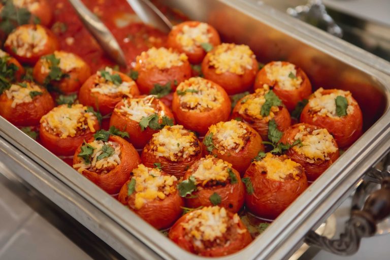 A tray of beautifully detailed stuffed tomatoes on a silver platter, perfect for weddings.