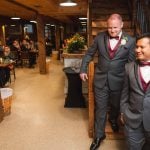 Two groomsmen descending stairs at a wedding reception.