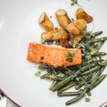 A wedding plate with salmon, green beans and potatoes.