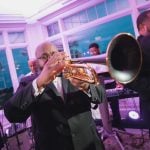 A man in a tuxedo playing a trumpet at a wedding reception.