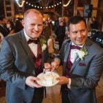 Two grooms celebrating their wedding with a cake at the reception.