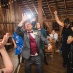 A man in a suit dancing at a wedding reception.