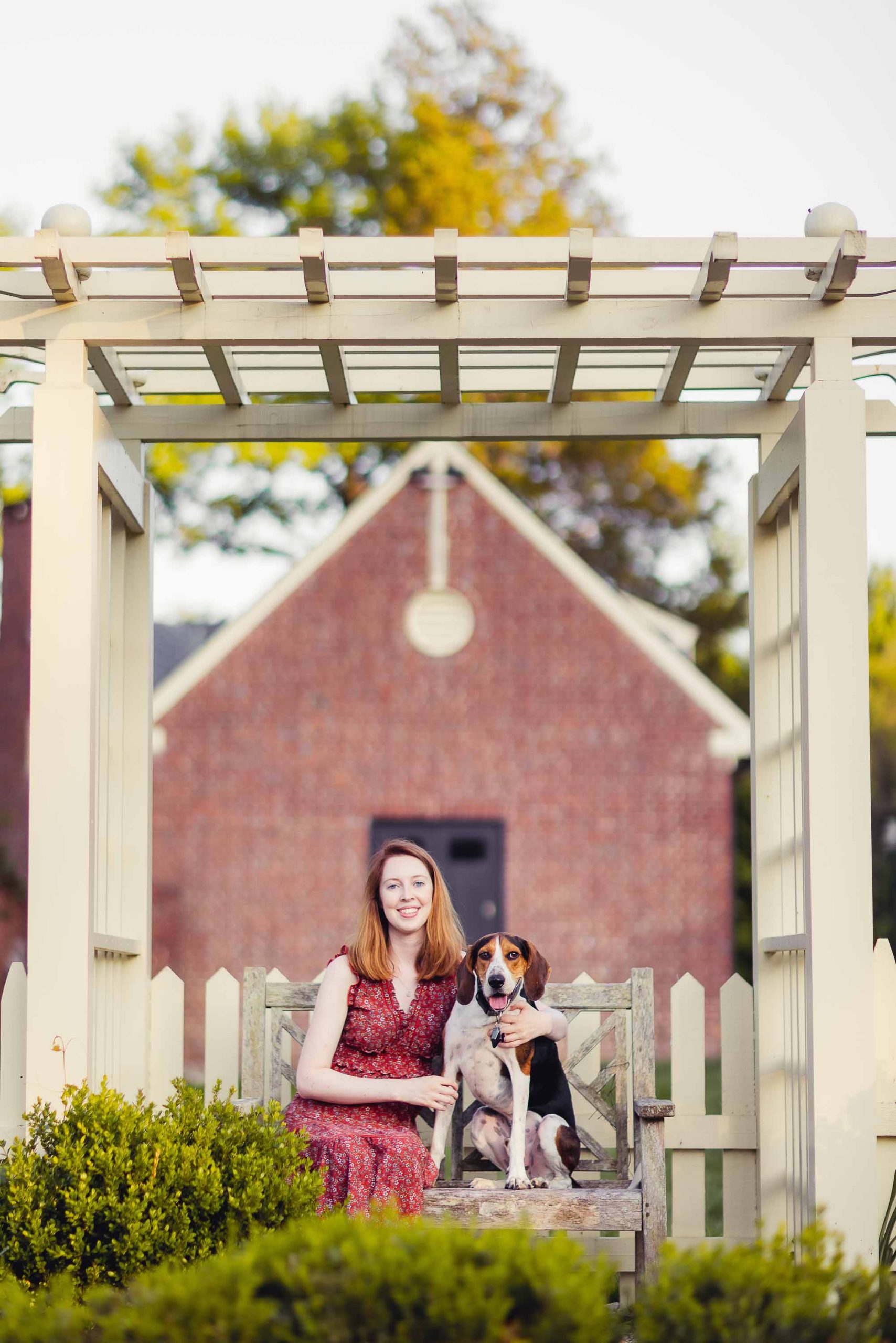 A woman with her dog sits on a bench at Montpelier Mansion.