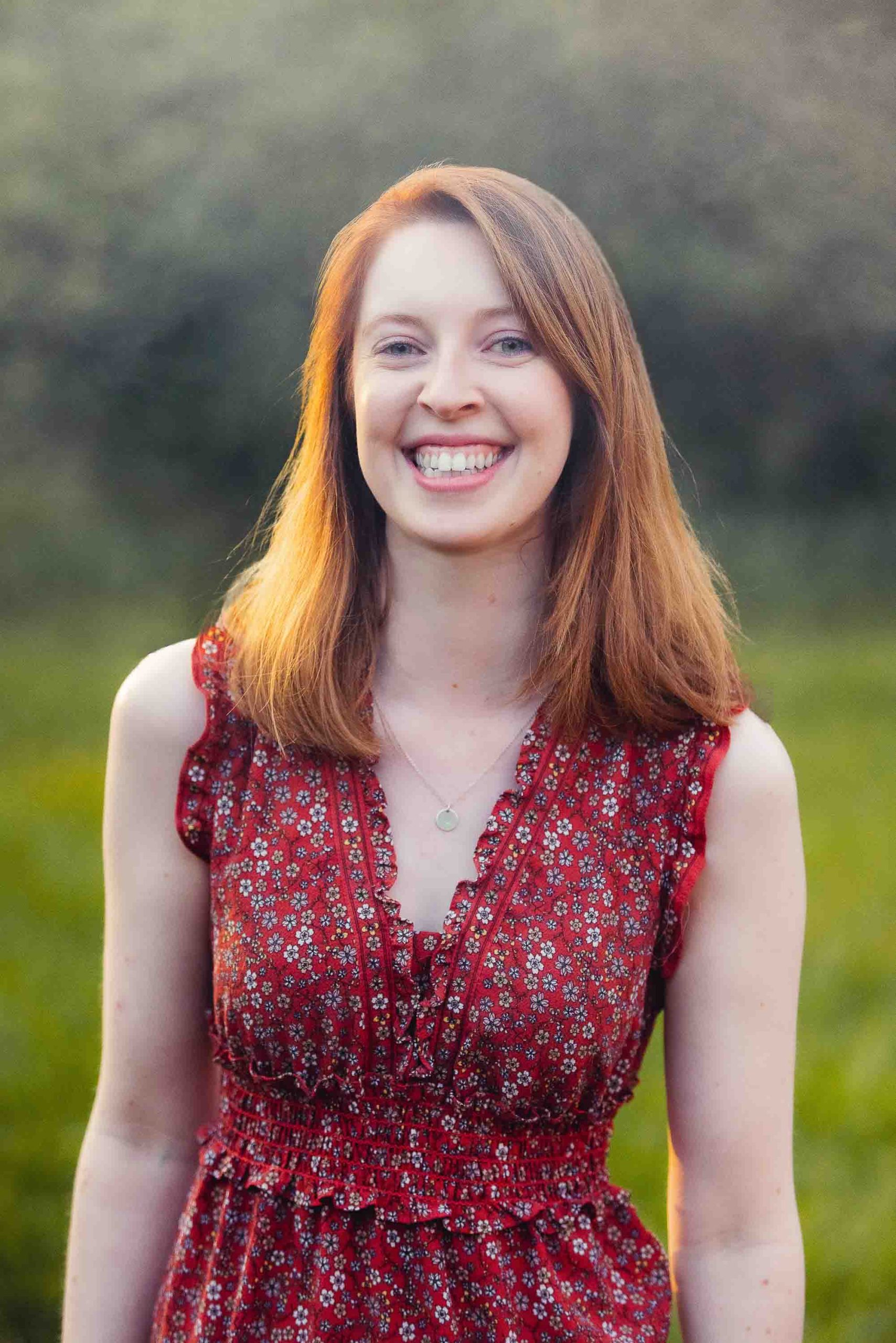 A woman in a red dress smiling in a field.

Keywords: Red dress