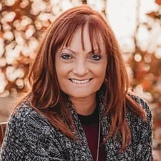 Logo: A woman with vibrant red hair sitting on a bench, representing Whispers of Joy.