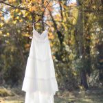 A white wedding dress hanging from a tree with beautiful fall foliage.