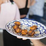 A person holding a plate of food at a birthday party.