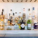 Many bottles of liquor are lined up on a shelf for a birthday party.