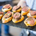 A man is holding a tray of appetizers at a birthday party.