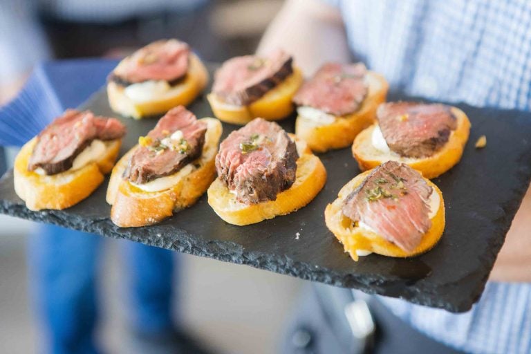 A man is holding a tray of appetizers at a birthday party.