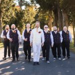 A group of groomsmen posing for a wedding portrait on a path.