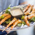 A man is holding a plate of shrimp at a birthday party.