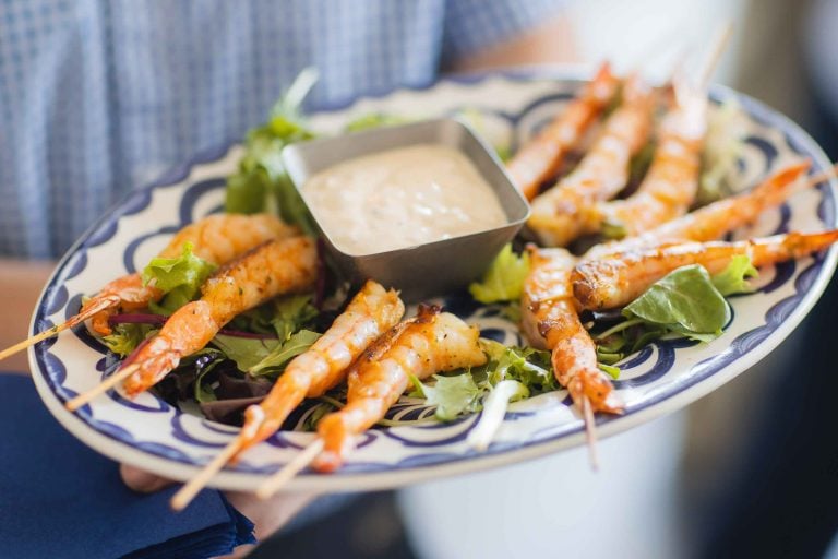 A man is holding a plate of shrimp at a birthday party.