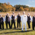 A wedding portrait of groomsmen standing in a field.