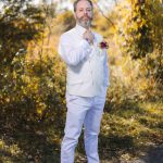 A man in a white suit is posing for a wedding portrait.